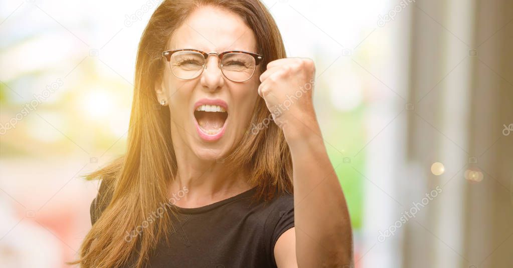 Middle age woman wearing black shirt and glasses irritated and angry expressing negative emotion, annoyed with someone