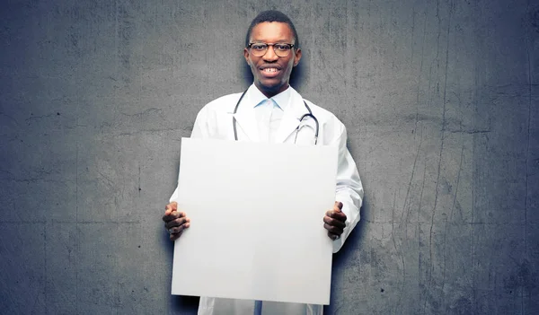 Young black doctor, medical professional holding blank advertising banner, good poster for ad, offer or announcement, big paper billboard