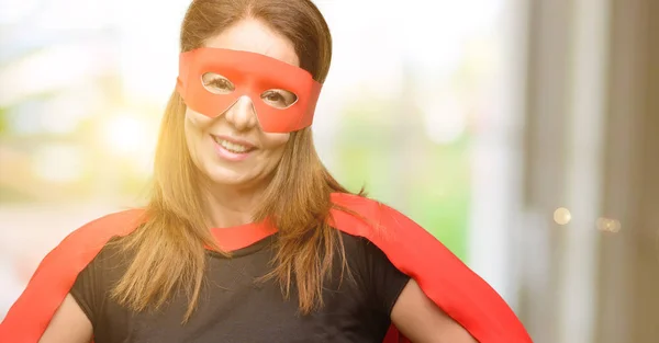 Middle age super hero woman wearing red mask and cape confident and happy with a big natural smile laughing