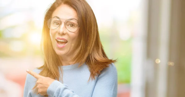 Midaldrende Kvinde Iført Uld Sweater Kølige Briller Peger Væk Side - Stock-foto