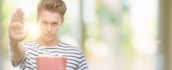 Mladý Pohledný Blondýn Jíst Popcorn Otevřenou Rukou Dělá Stopku Vážnou — Stock fotografie