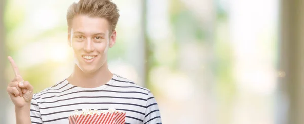 Jovem Homem Loiro Bonito Comendo Pipocas Muito Feliz Apontando Com — Fotografia de Stock