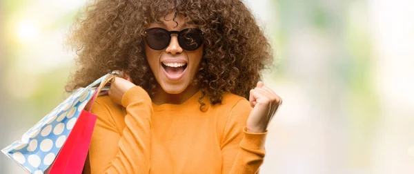 Mujer Afroamericana Sosteniendo Bolsas Compras Gritando Orgulloso Celebrando Victoria Éxito —  Fotos de Stock