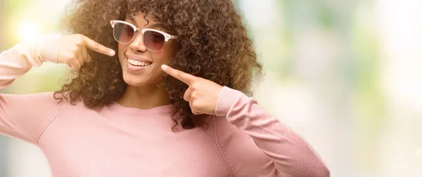 Mujer Afroamericana Con Gafas Sol Rosas Sonriendo Confiada Mostrando Señalando — Foto de Stock