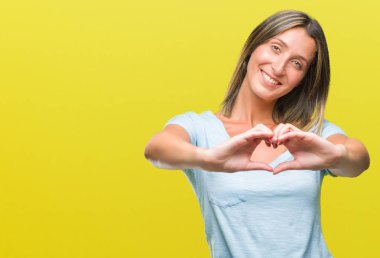 Genç güzel kadın kalp simgesi ve elleriyle şekil gösterilen aşık gülümseyen izole arka plan yüzünden. Romantik kavramı.