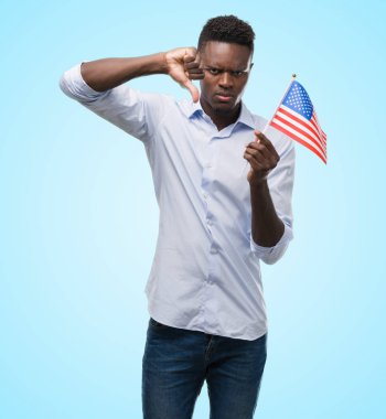 Kızgın yüz, eksi işareti aşağı antipati başparmak ile gösterilen, ret kavramı ile ABD bayrağı tutan genç Afro-Amerikan adam