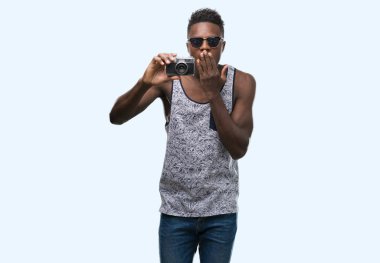 Vintage fotoğraf makinesi kapak ağız elle hata, korku, ifade için utanç ile şok tutan genç Afro-Amerikan adam sessizce, gizli kavramı korkuttu