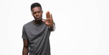 Gri t-shirt giyen genç Afro-Amerikan adam elin avuç ile şarkı stop yapıyor. Negatif ve ciddi bir jest yüz ifadesiyle uyarı.