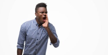 Bağırarak ve ağzı üzerinde el ile yan için çığlık mavi gömlek giymiş genç Afro-Amerikan adam. İletişim kavramı.