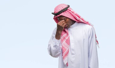 Geleneksel keffiyeh izole arka plan yorgun sürtünme burun ve göz yorgunluğu ve baş ağrısı duygu üzerinde giyen genç Arapça Afrika adam. Stres ve hayal kırıklığı kavramı.