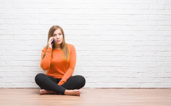 Junge Erwachsene Frau Sitzt Auf Dem Boden Über Weißen Backstein — Stockfoto