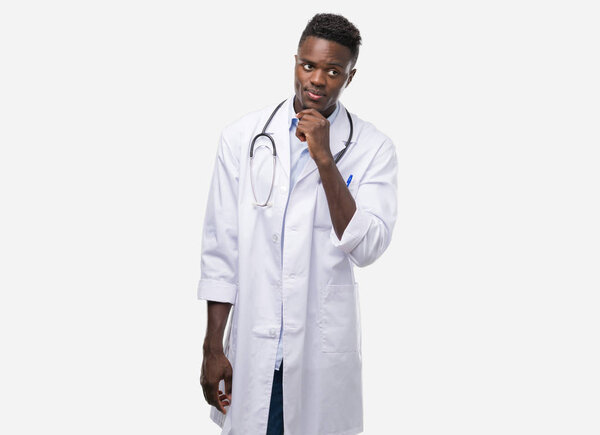 Young african american man wearing doctor coat serious face thinking about question, very confused idea