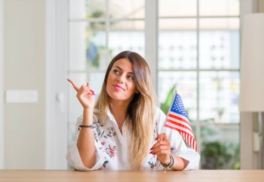 Genç kadın evde Amerika Birleşik Devletleri bayrağı çok mutlu el ve parmak ile tarafına işaret tutan