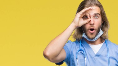 Genç yakışıklı adam uzun saçlı ok jest sürpriz yüz, göz parmaklarının arasından seyir şok yapıyor izole arka plan üzerinde doktor. İmansız ifade.