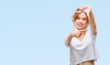 Genç güzel kadın elle yapma çerçeve ve parmakları ile mutlu yüz gülümseyen izole arka plan yüzünden. Yaratıcılık ve Fotoğrafçılık kavramı.