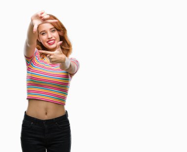 Genç güzel kadın elle yapma çerçeve ve parmakları ile mutlu yüz gülümseyen izole arka plan yüzünden. Yaratıcılık ve Fotoğrafçılık kavramı.