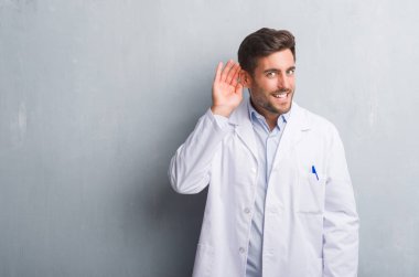 Bir işitme söylenti ya da dedikodu için dinleme kulak üzerinde el ile gülümseyen gri grunge duvar giyen üzerinde profesyonel yakışıklı genç beyaz ceket. Sağırlık kavramı.