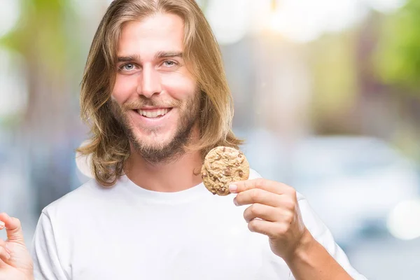 分離背景側の手と指で指す非常に幸せにチョコレート クッキーを食べて髪の長い若いハンサムな男 — ストック写真