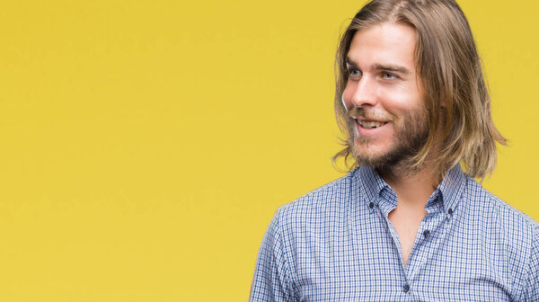 Young handsome man with long hair over isolated background looking away to side with smile on face, natural expression. Laughing confident.