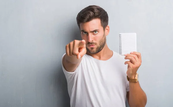 Stilig Ung Man Över Grå Grunge Väggen Håller Tom Anteckningsbok — Stockfoto