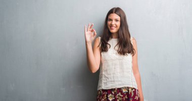 Genç esmer kadın parmakları, mükemmel sembolü olan ok işareti yapıyor grunge gri duvarın üzerinden