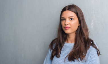 Grunge gri duvar acımak yüz ciddi düşünüyorum üstünde kendine güvenen bir ifade ile genç esmer kadın