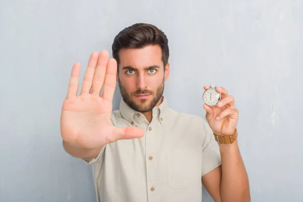 Guapo Joven Sobre Pared Grunge Gris Sosteniendo Cronómetro Con Mano — Foto de Stock