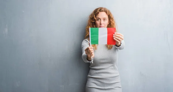 Young Redhead Woman Grey Grunge Wall Holding Flag Italy Confident — Stock Photo, Image