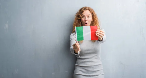 Young Redhead Woman Grey Grunge Wall Holding Flag Italy Scared — Stock Photo, Image