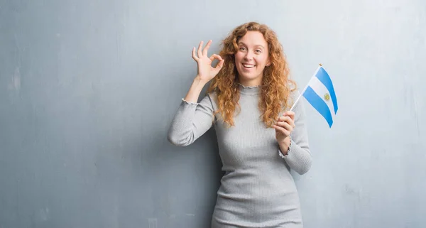 Mulher Ruiva Jovem Sobre Parede Grunge Cinza Segurando Bandeira Argentina — Fotografia de Stock