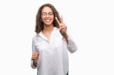 Zafer işareti yapıyor parmak gösterilen kamera seyir gülümseyen güzel genç İspanyol kadın. İki numaralı.