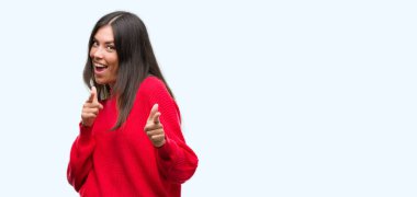 Genç güzel İspanyol kırmızı kazaklı işaret parmak kamera ile mutlu ve komik yüz için giyiyor. İyi enerji ve vibes.