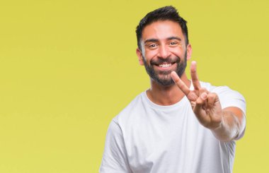 Zafer işareti yapıyor parmak gösterilen kamera seyir gülümseyen izole arka plan yetişkin İspanyol adam. İki numaralı.