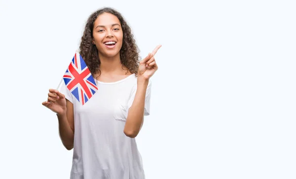 非常に幸せな側の手と指で指すイギリスの旗を保持している若いヒスパニック系女性 — ストック写真