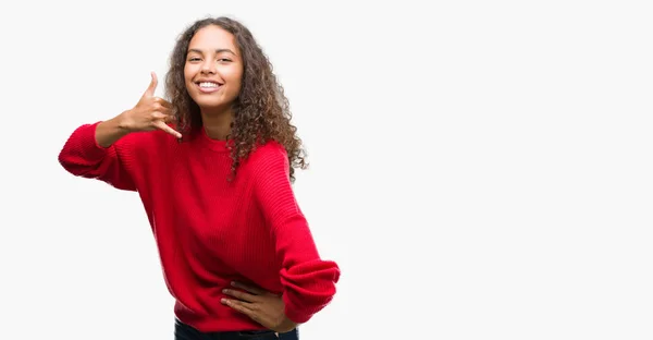 笑みを浮かべて赤いセーターを着ている若いヒスパニック系女性の手と電話で話しているように指で電話のジェスチャーを行います 通信の概念 — ストック写真