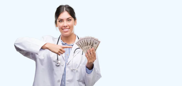 Joven Doctora Hispana Sosteniendo Dólares Muy Feliz Señalando Con Mano — Foto de Stock