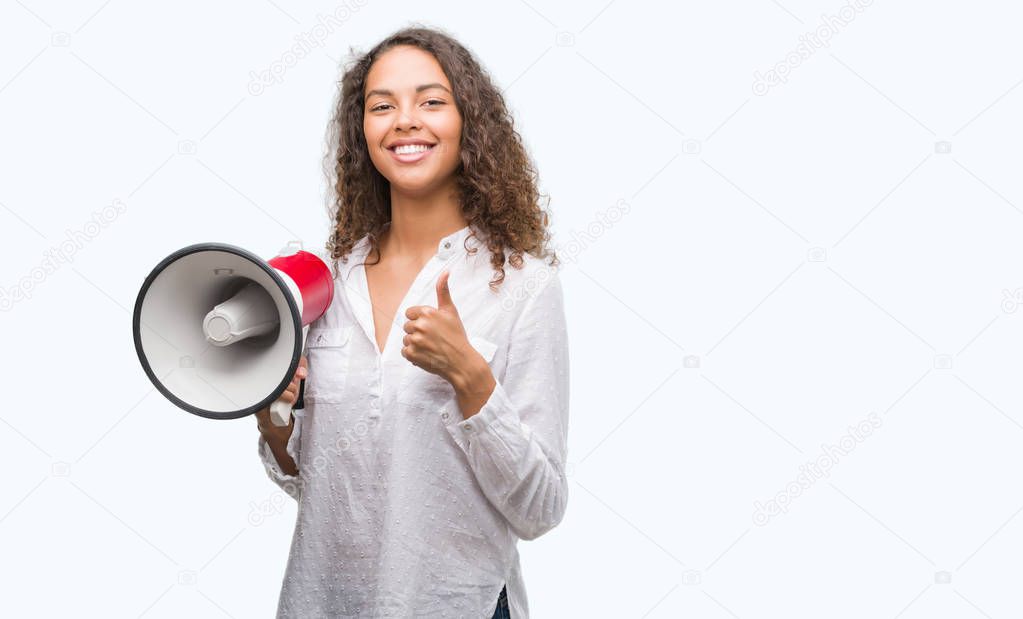 Young hispanic woman holding megaphone happy with big smile doing ok sign, thumb up with fingers, excellent sign