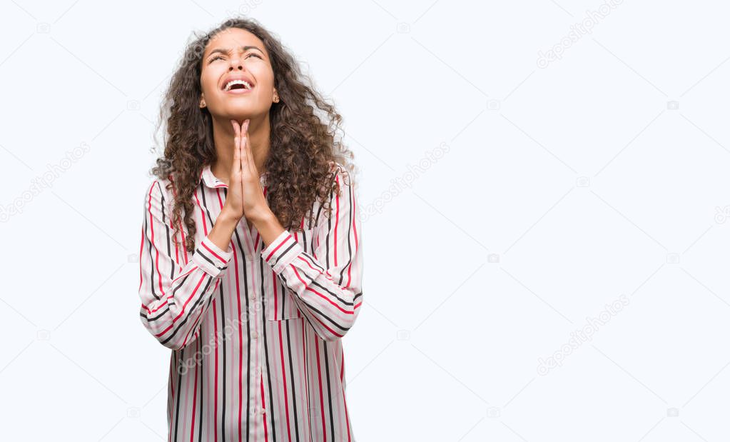 Beautiful young hispanic woman begging and praying with hands together with hope expression on face very emotional and worried. Asking for forgiveness. Religion concept.