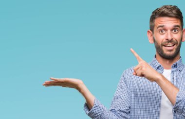 Hayret ve el ile sunulması ve parmak ile işaret ederken kameraya gülümseyen izole arka plan üzerinde beyaz t-shirt giyen genç yakışıklı adam.