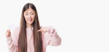 Kendisi için sürpriz yüz işaret parmağı ziyaret Kart tutan izole arka plan üzerinde Genç Çinli kadın