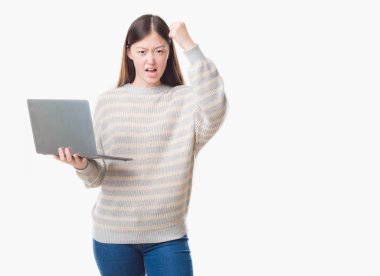 Bilgisayar dizüstü kullanarak izole arka plan üzerinde Genç Çinli kadını rahatsız ve boşa çıkarmak ile öfke, çılgın da yükseltilmiş el ile bağırmaya kavramı öfke