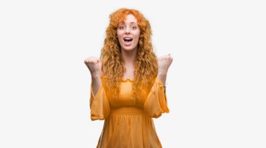 Genç Kızıl saçlı kadın kutluyor şaşırttı ve başarı için kaldırdı kollarını açarak hayret ve gözleri açık. Kazanan kavramı.