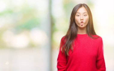 İzole arka plan yapma balık yüzüne dudaklı, çılgın ve komik bir jest kış kazak giyen genç Asyalı kadın. Komik ifade.