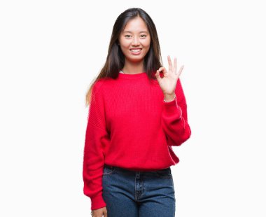 İzole arka plan el ve parmaklar ok işaretiyle yapıyor olumlu gülümseyen üzerinde kış kazak giyen genç Asyalı kadın. Başarılı ifade.
