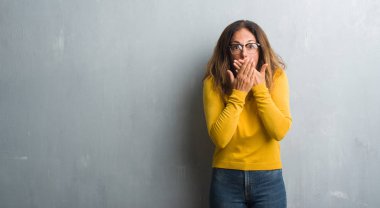 Orta yaş gri duvar eller için hata ile ağız kapsayan şok gözlüklü İspanyol kadın. Gizli kavramı.