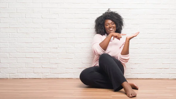 Молодая Африканская Американка Сидящая Полу Наушниках Удивлена Улыбается Камеру Показывая — стоковое фото