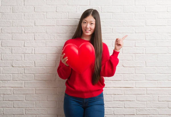 Junge Chinesin Verliebt Über Ziegelmauer Hält Rotes Herz Sehr Glücklich — Stockfoto