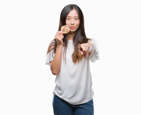 Joven Mujer Asiática Comiendo Galletas Chocolate Sobre Fondo Aislado Señalando —  Fotos de Stock