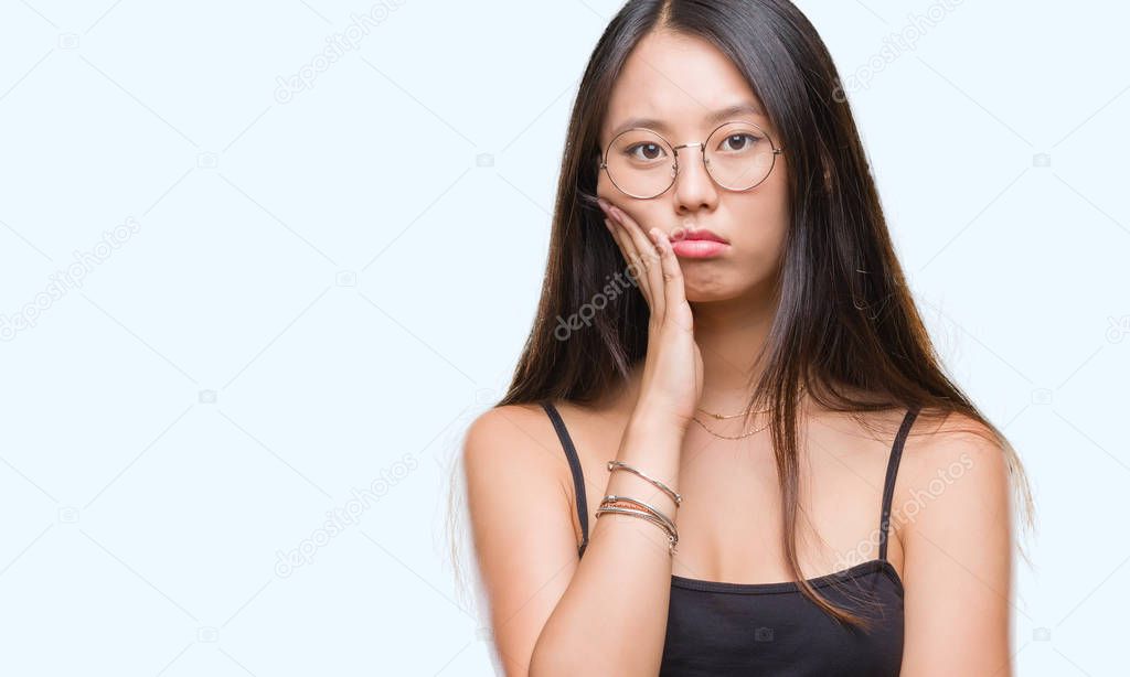 Young asian woman wearing glasses over isolated background thinking looking tired and bored with depression problems with crossed arms.