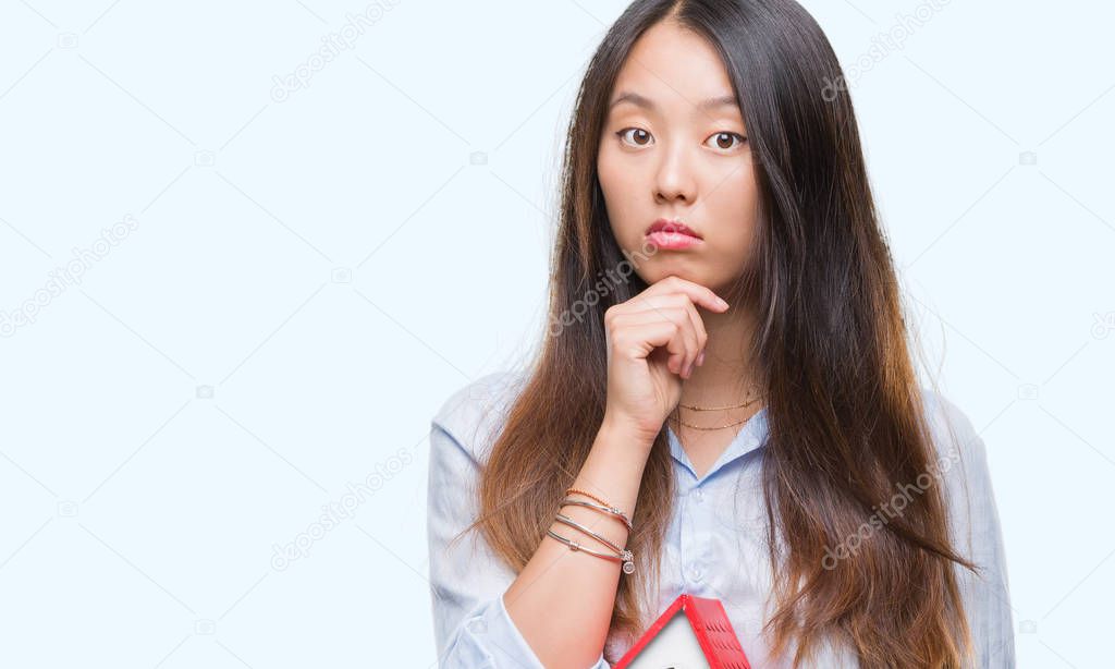 Young asian woman real state agent holding house isolated background serious face thinking about question, very confused idea